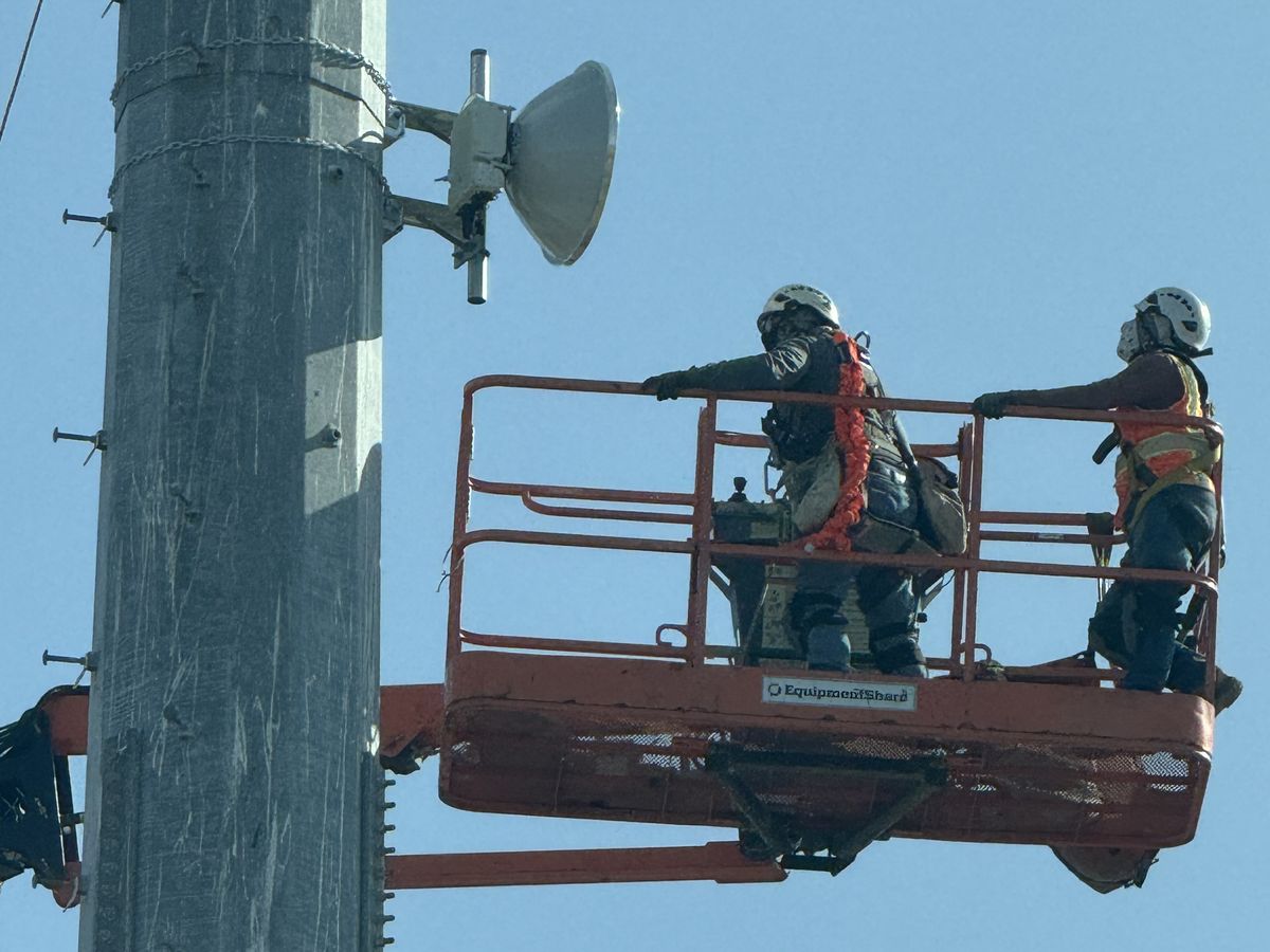 Two CVI crew members in a lift installing a backhaul dish